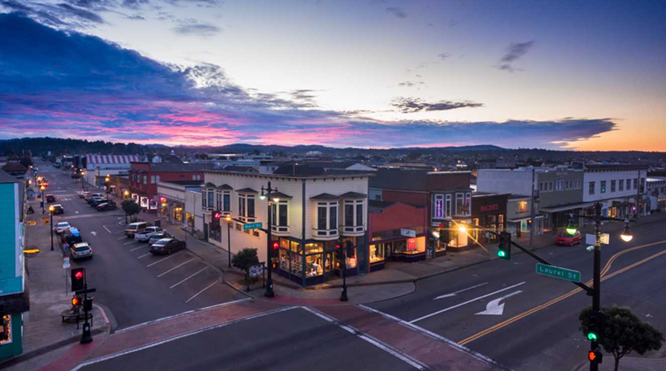 A picturesque town street bathed in warm hues of orange and pink during a serene sunset - Copy