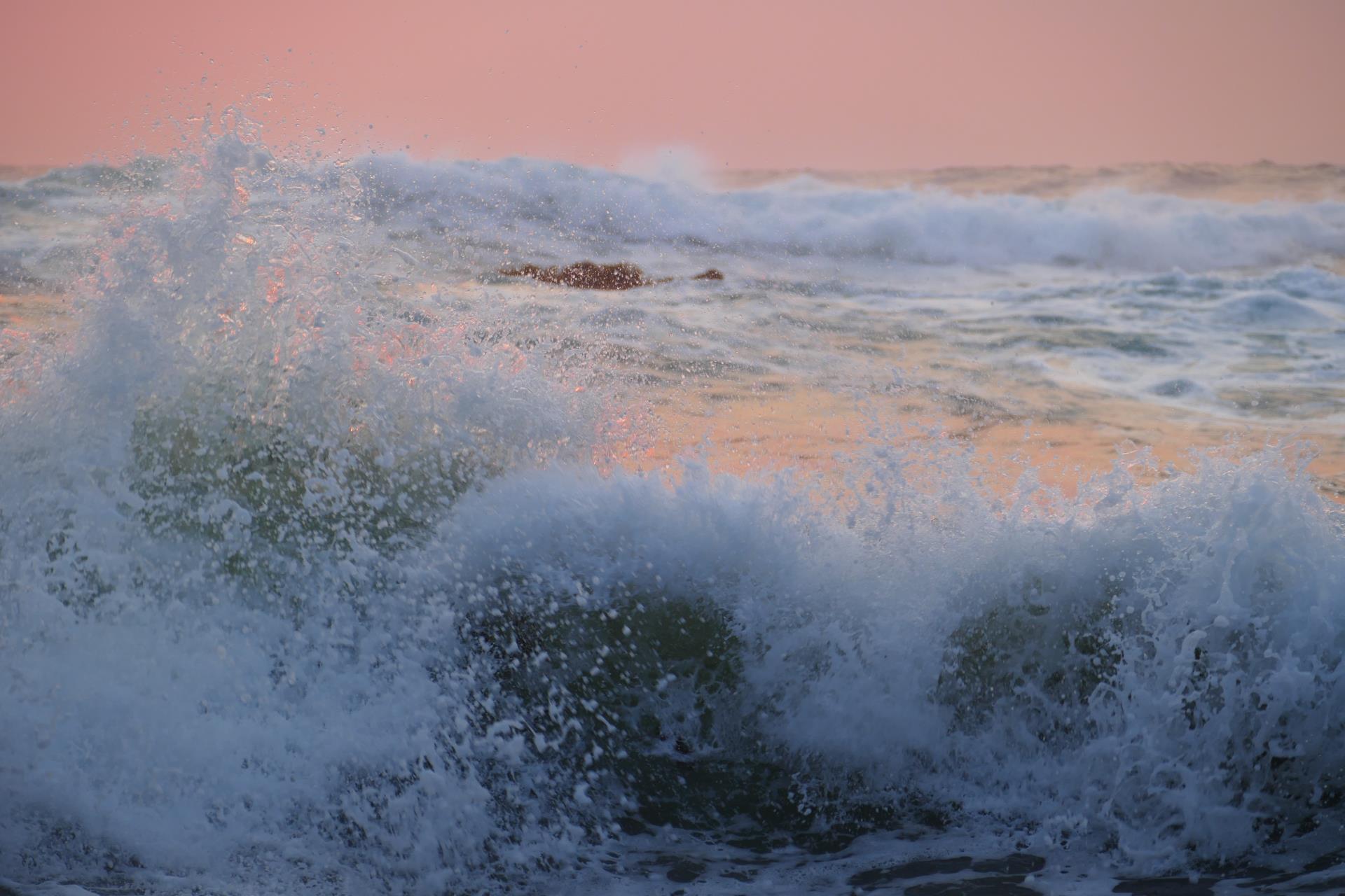 A large wave crashes powerfully into the ocean