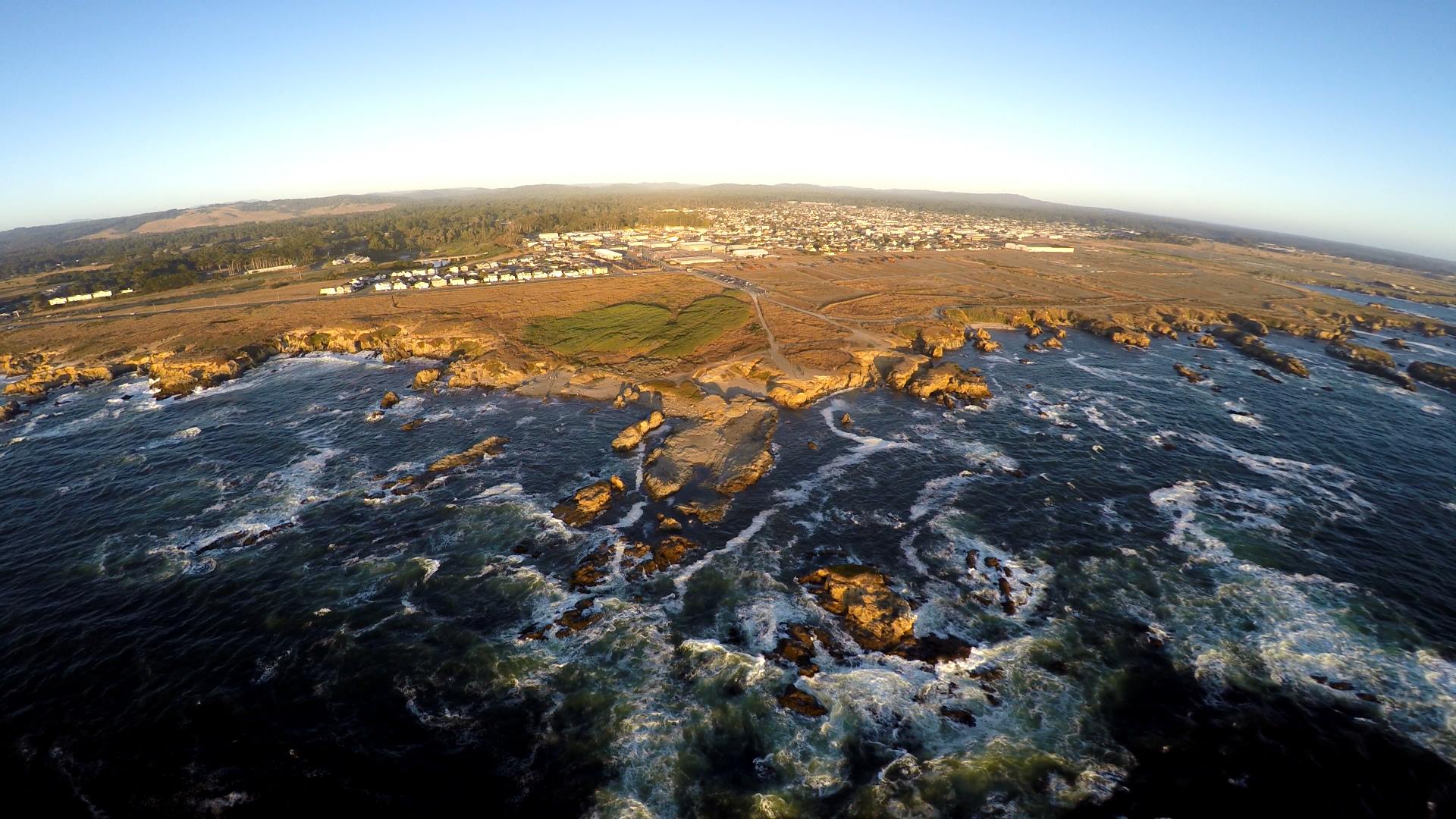 Aerial view showcasing the vast ocean meeting the rugged coastline, highlighting waves and sandy shores