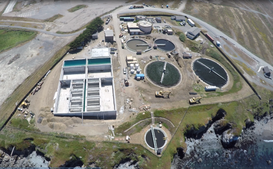 Aerial view of a large water treatment plant, showcasing multiple tanks and filtration systems surrounded by greenery - 1