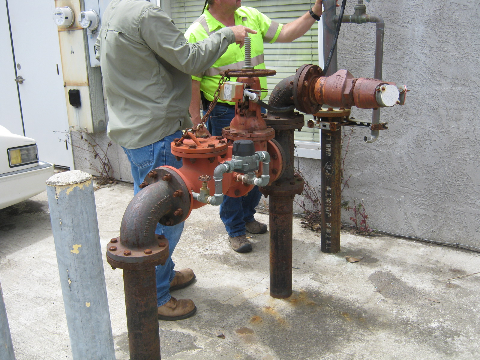 A man stands beside a red fire hydrant on a city street, wearing casual clothing a